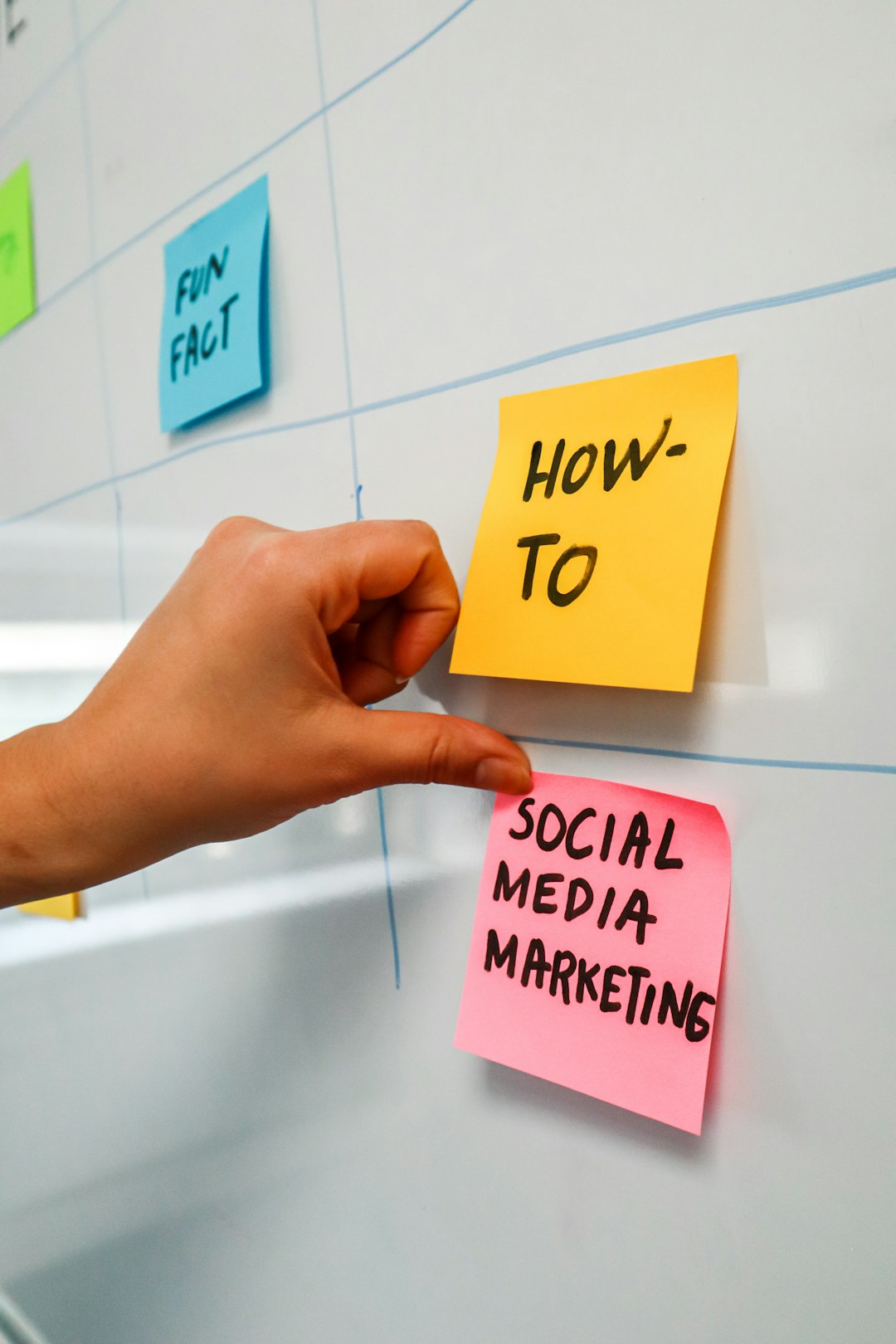 mobile-01 Person sticking a post-it on a white board with the words Social Media Marketing written on it
